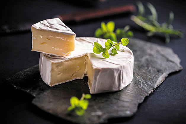 Ein aufgeschnittener Camembert auf einer Schiefernplatte