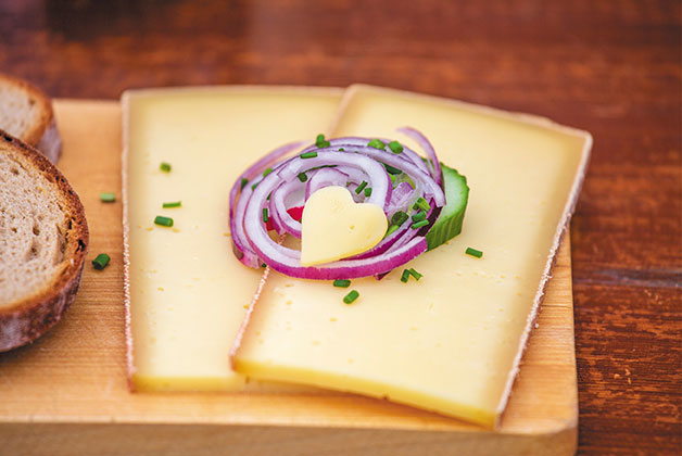 Zwei Scheiben Hartkäse auf einem Holzbrett