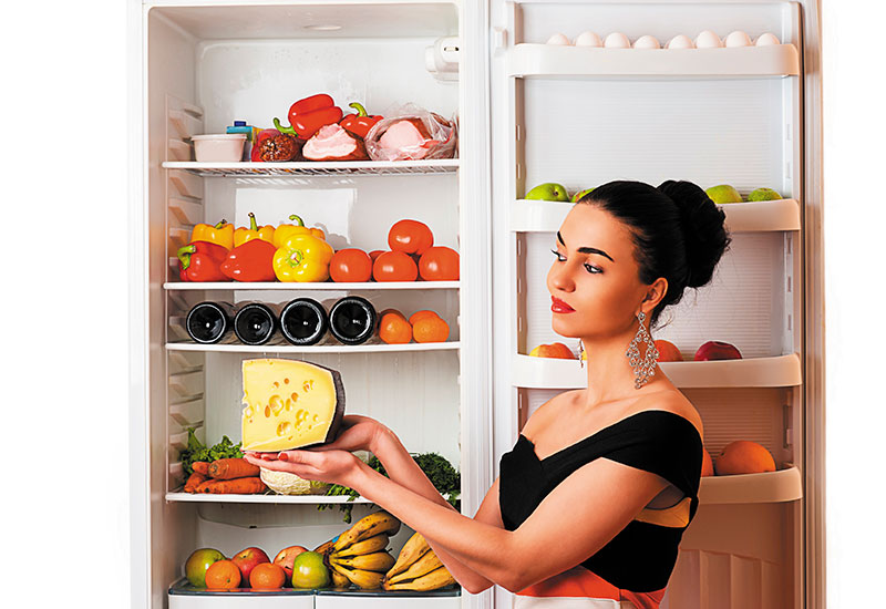 Eine Frau lagert Käse im Kühlschrank