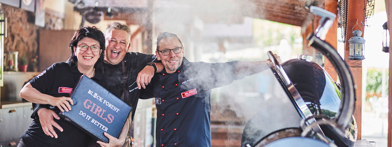 Das Team von Forum Culinaire, Gehard Volk, Maria Bruder und Heiner Haseleid präsentieren sich vor einem brennenden Grill