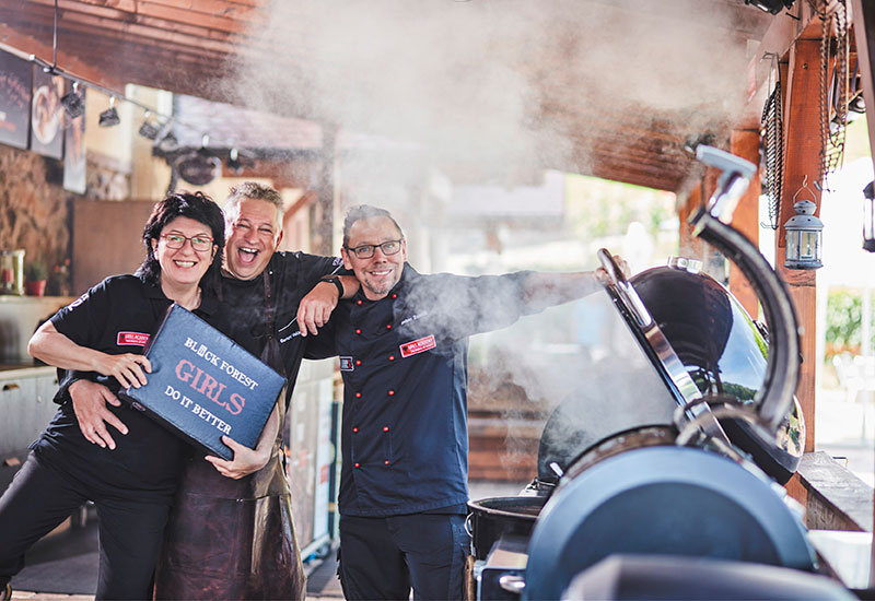 Das Team von Forum Culinaire präsentiert sich vor einem brennenden Grill