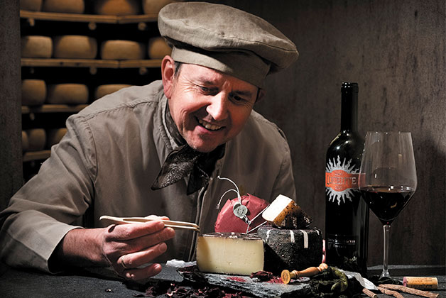Affineur Hansi Baumgartner arbeitet an seinem Luce Käse. Dabei eine Flasche Luce Wein und ein Rotweinglas