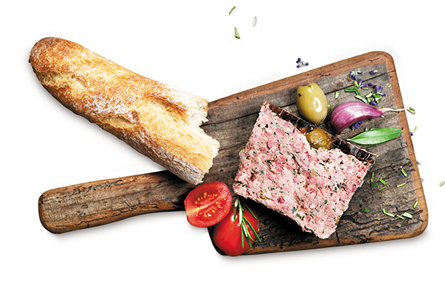 Ein Holzschneidebrett, ein Stück Brot, eine Scheibe Pate und rote Zwiebeln mit Tomaten dekorativ angerichtet