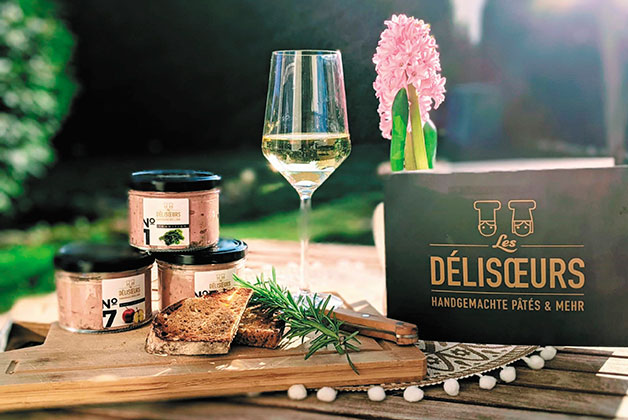 Ein Tisch im Garten, 3 Gläser Pates, ein Glas Weißwein und eine Karte von Les Delisoeurs