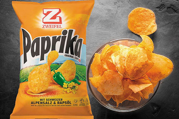 Eine Tüte Zweifel Chips neben einer Schüssel Chips auf grauem Hintergrund